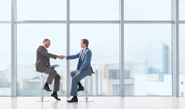 Two business man in suit shaking hands on the work office.