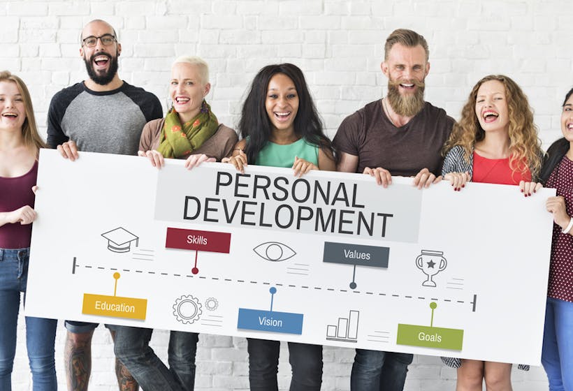 A group of employees holding up a board with personal development objectives on it.
