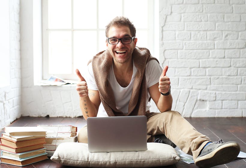 Young man smiling in front of the laptop.